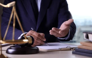 Pessoa ao lado de símbolo do direito sobre a mesa gesticulando