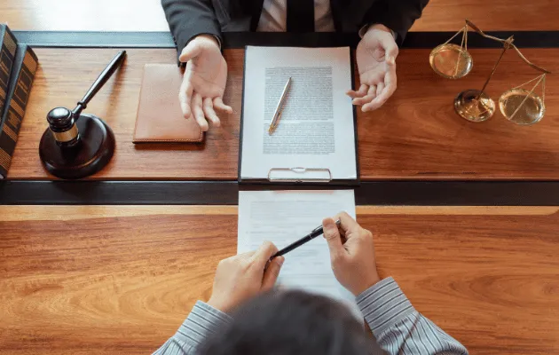 Pessoas em mesa analisando representação de advogado