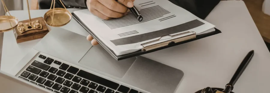 Pessoa escrevendo em documento e trabalhando com uso de computador