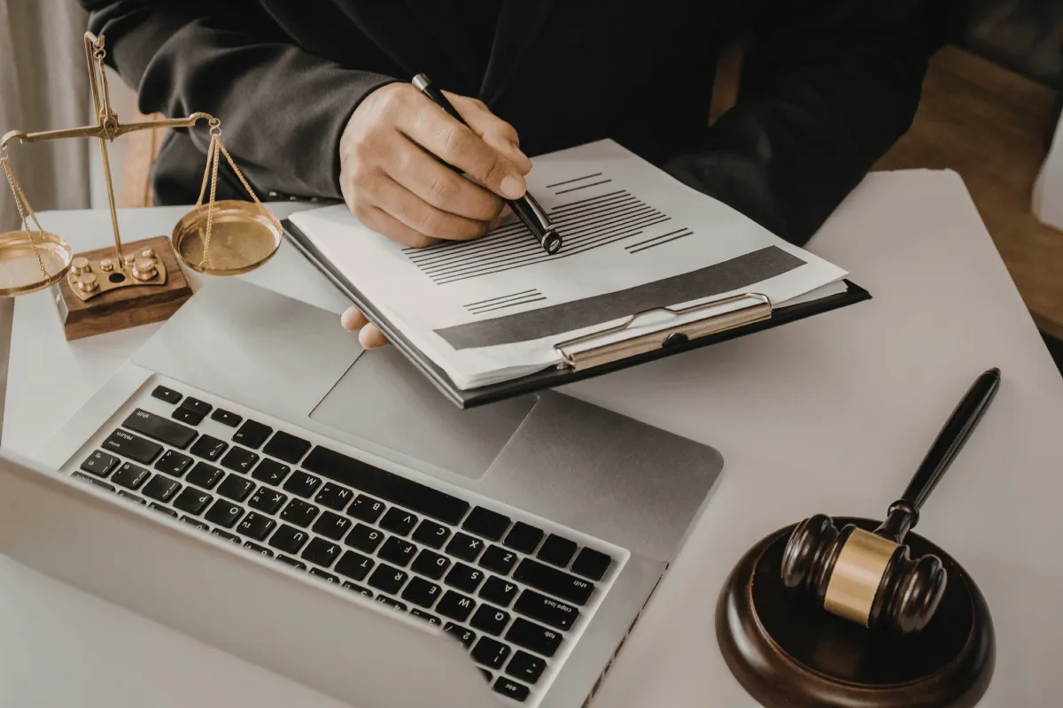 Pessoa escrevendo em documento e trabalhando com uso de computador